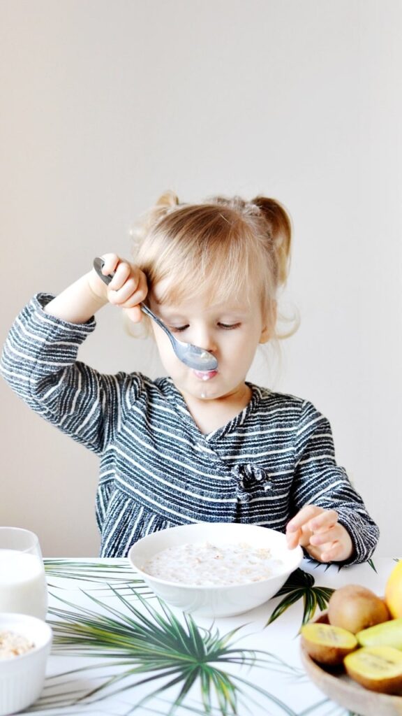 Niño pequeño comiendo con las manos, explorando la textura de los alimentos - beneficios del desarrollo sensorial en niños